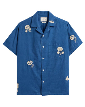 Blue shirt with floral embroidery on a beige background