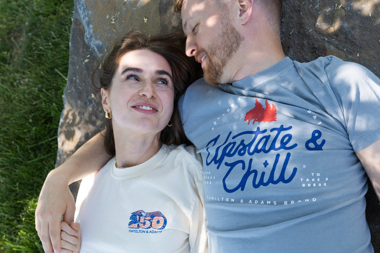 Two people lying on a rock with grass in the background