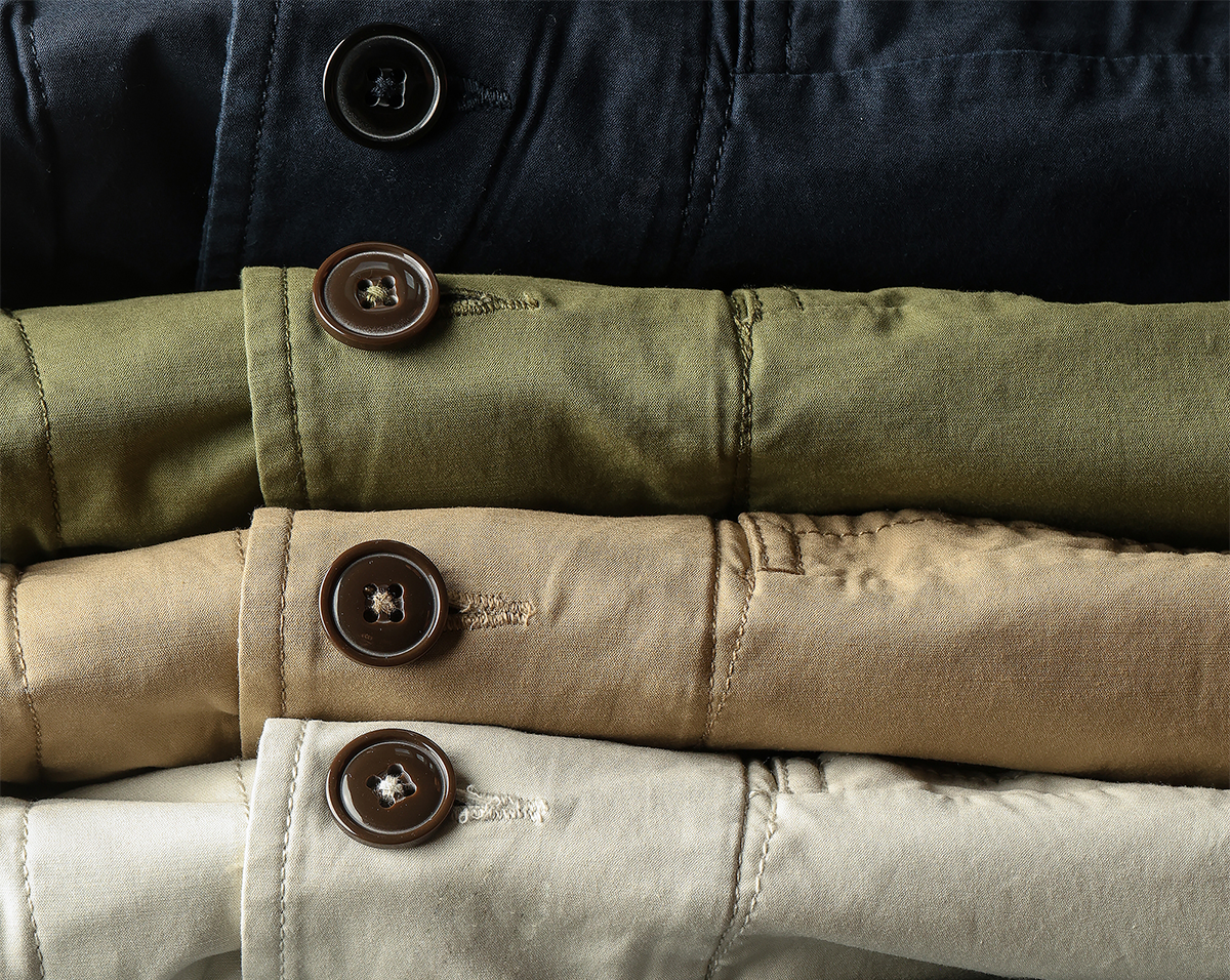 Stack of folded jackets in various colors with button details.