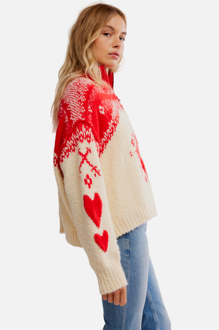 Woman wearing a red and white patterned sweater with hearts on a plain background