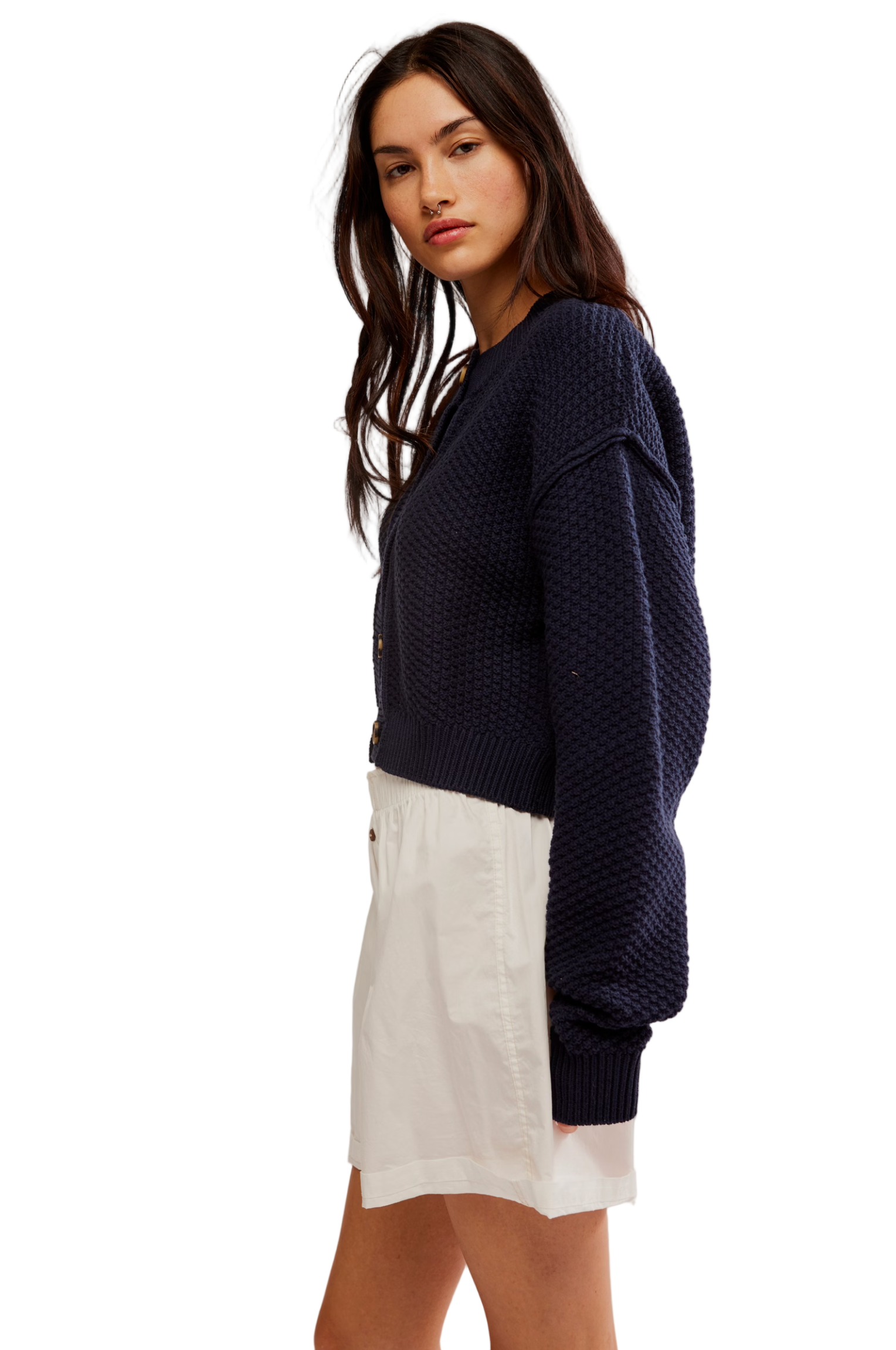 Woman wearing a navy blue sweater and white shorts on a plain background