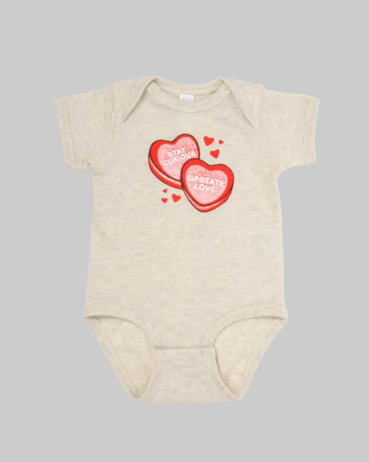 Beige baby onesie with red heart design on a white background