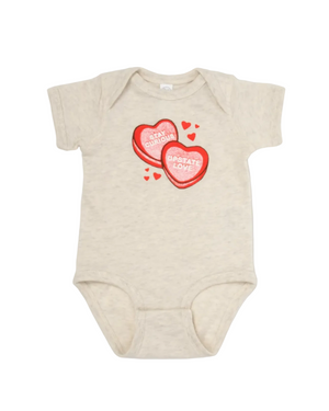 Beige baby onesie with red heart design on a white background