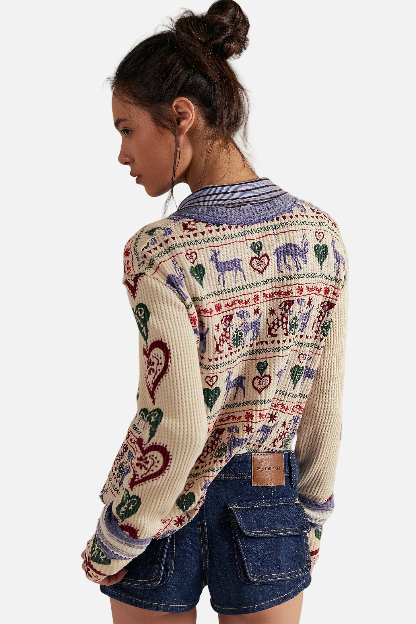 Woman wearing a patterned sweater with hearts and animals on a plain background