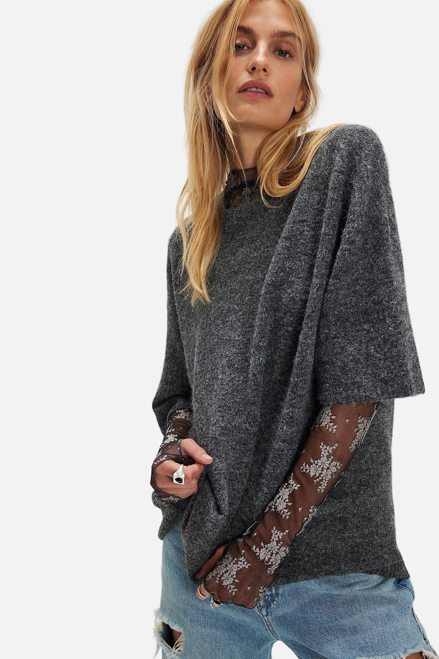 Woman wearing a dark gray poncho with lace trim on a white background